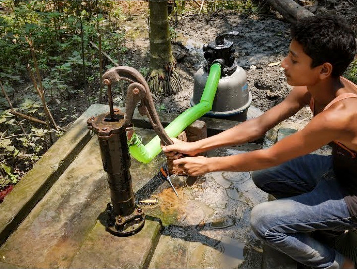 A boy in rural Bangladesh uses a water pump equipped with a PurifAid filter.