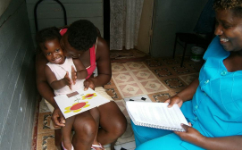 0461-03 Community worker and Mother congratulate baby for completing puzzle in home visiting program in Kingston, Jamaica